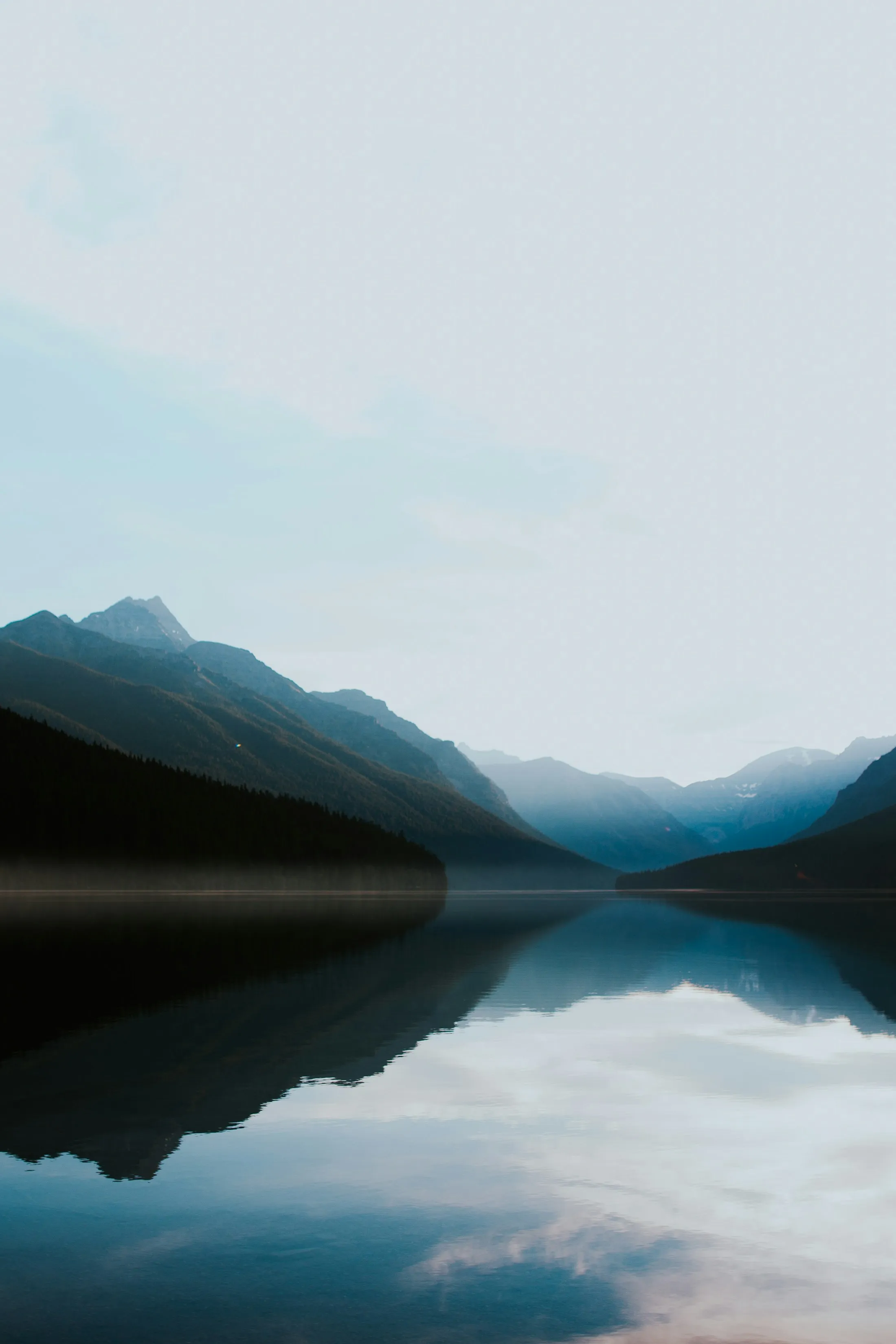 A still mountain lake beneath a pale evening sky